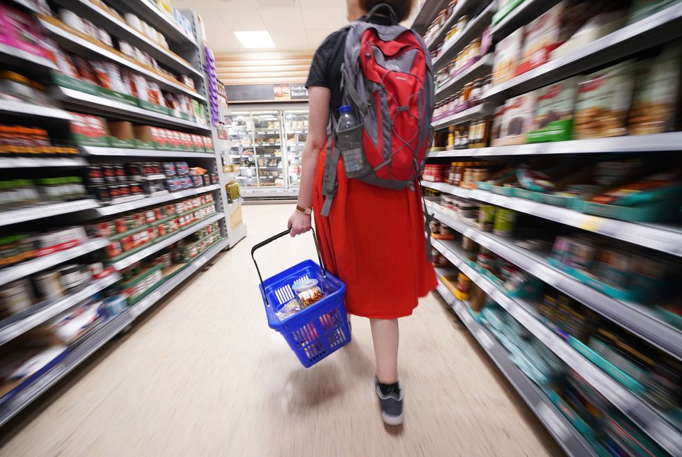 A shopper walking through the aisle of a Tesco supermarket