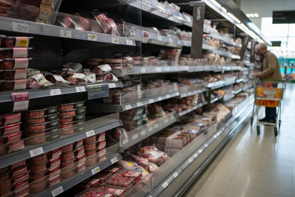 A shopper walking through the fresh meat aisle in a branch of Waitrose in south London