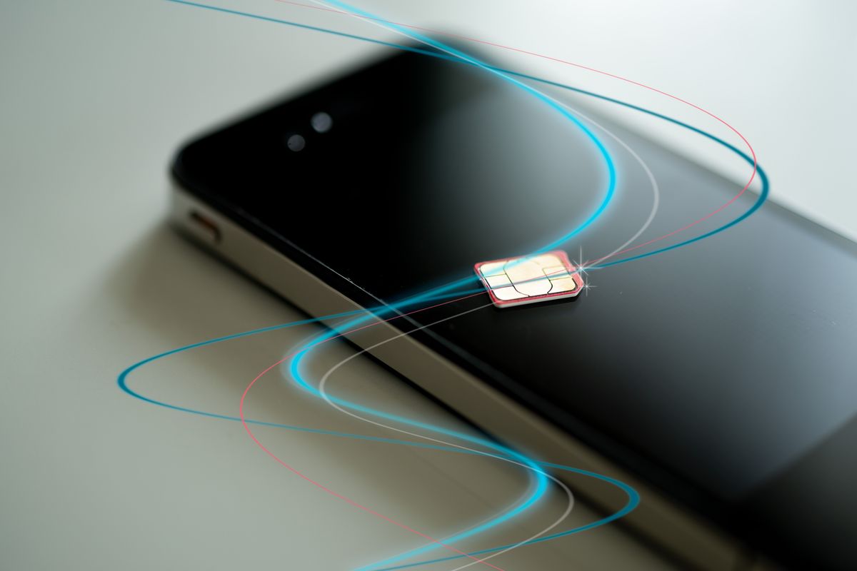 a sim card is pictured lying ontop of a smartphone