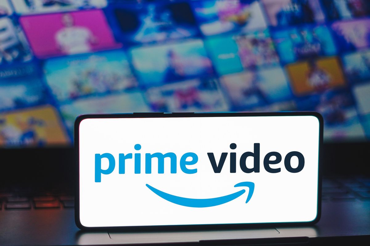 a smartphone with the prime video logo on-screen is pictured resting on a laptop with artwork for the biggest exclusive shows