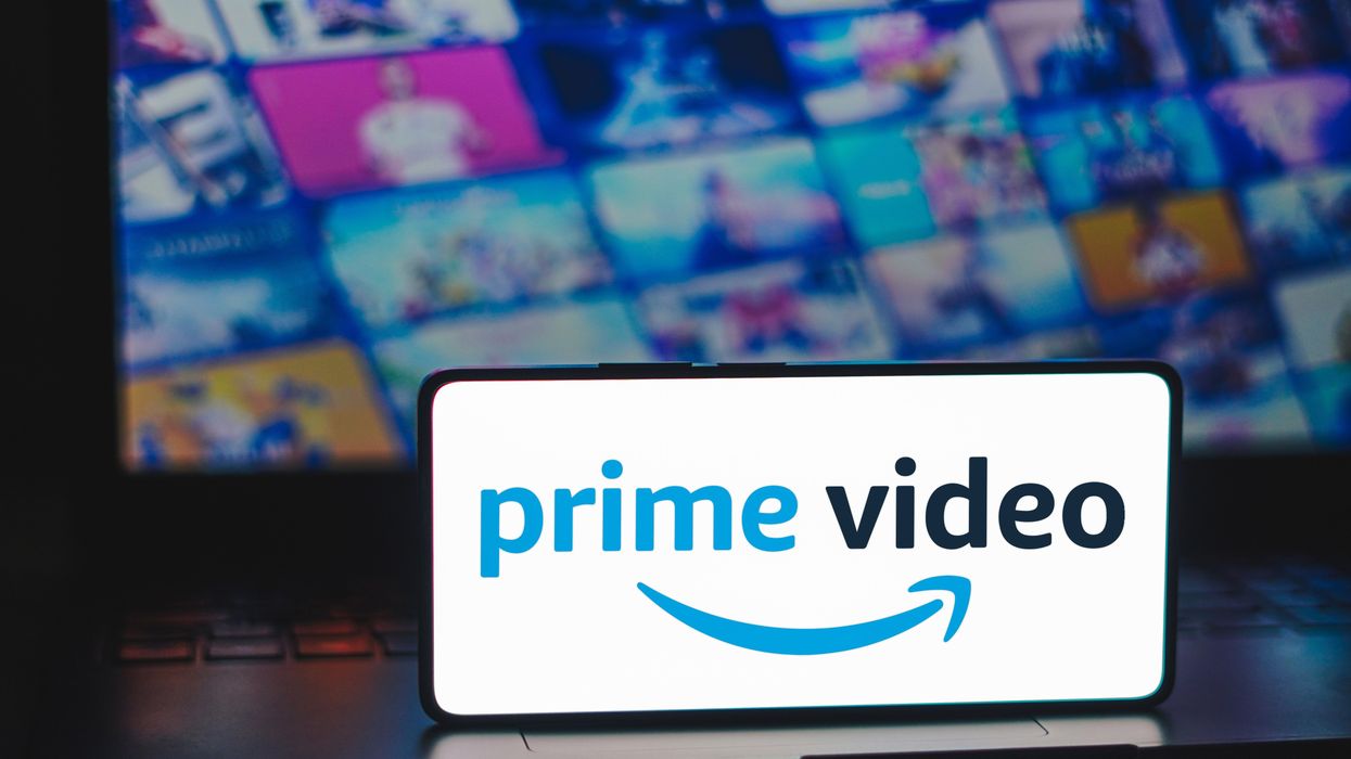 a smartphone with the prime video logo on-screen is pictured resting on a laptop with artwork for the biggest exclusive shows