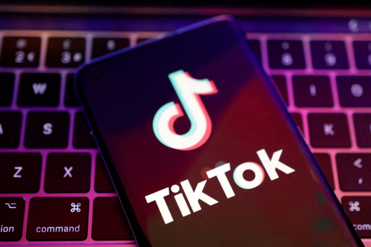 a smartphone with the tiktok logo on-screen is pictured on a computer keyboard 
