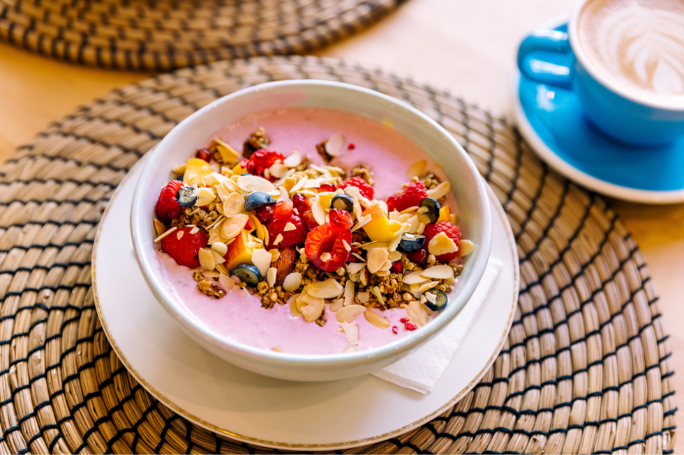 A smoothie bowl topped with blueberries, raspberries and toasted coconut flakes