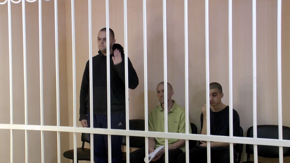 A still image, taken from footage of the Supreme Court of the self-proclaimed Donetsk People's Republic, shows Britons Aiden Aslin, Shaun Pinner and Moroccan Brahim Saadoun captured by Russian forces during a military conflict in Ukraine, in a courtroom cage at a location given as Donetsk, Ukraine.