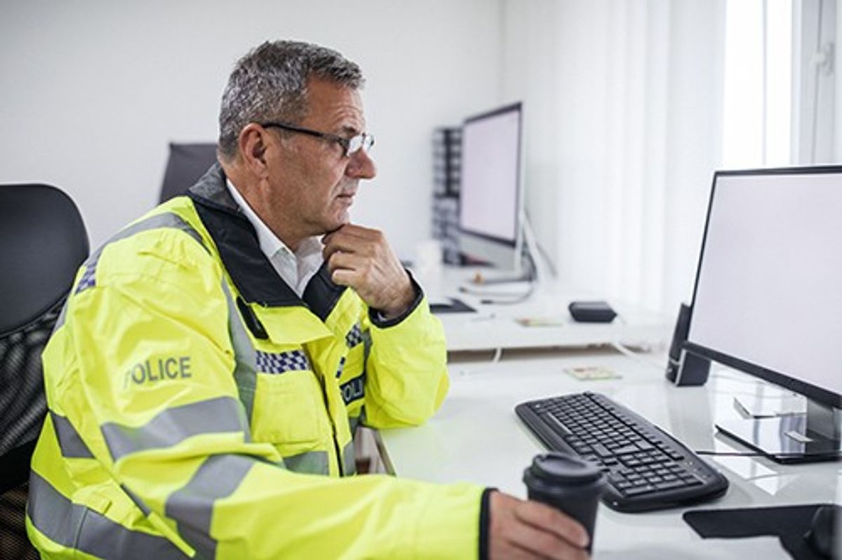 A stock image of a police officer using a computer