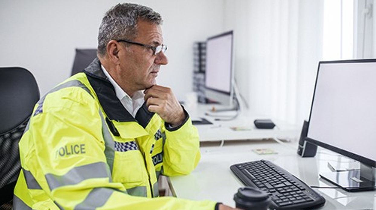 A stock image of a police officer using a computer