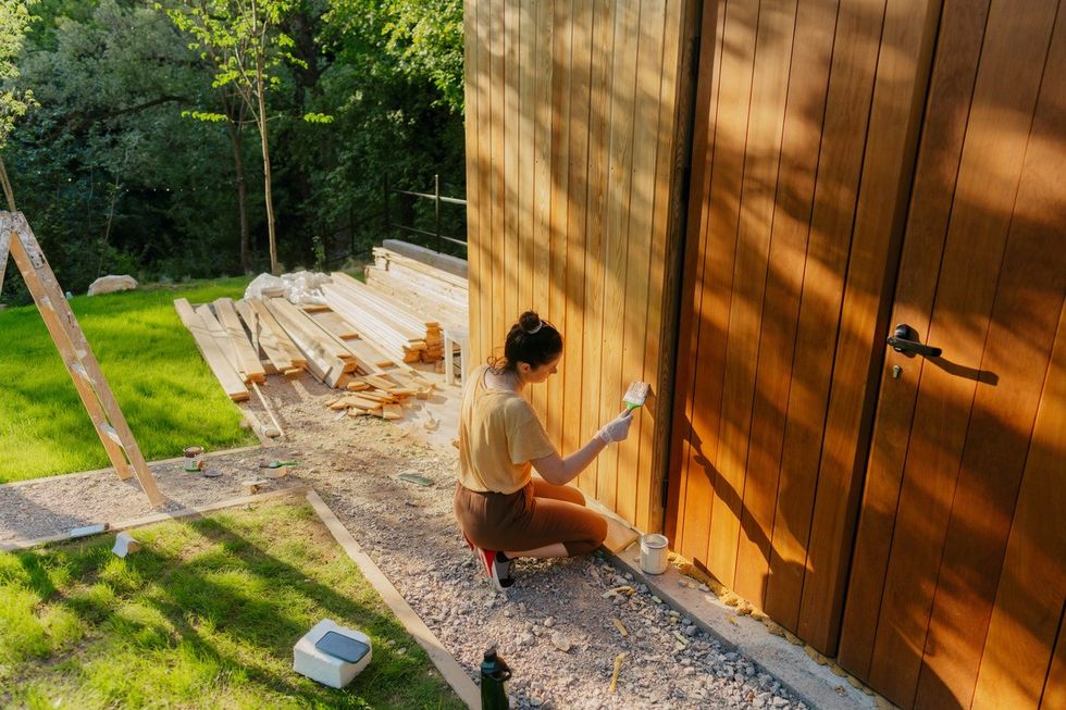 A stock image of a woman painting a shed