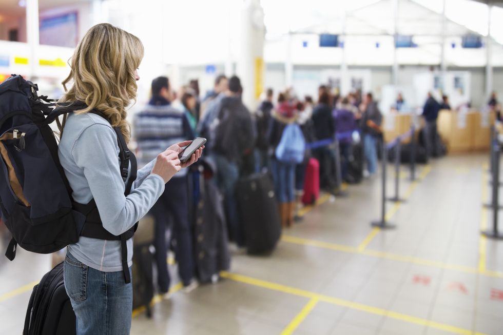 A stock image of a woman waiting at a busy airport