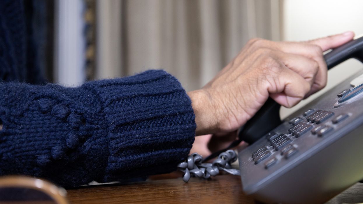 A stock image of an old person using a landline phone