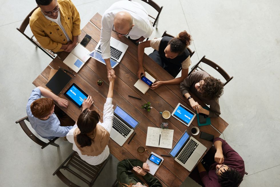 A stock image of workers at a desk on laptops