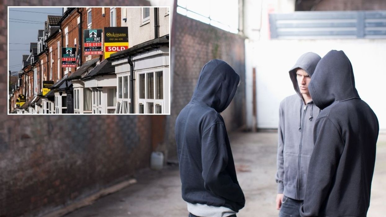 A street with 'For Sale' signs and a group of boys in hoodies