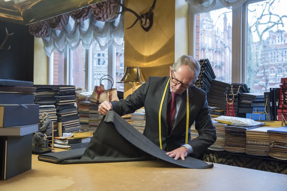 A tailor altering an item of clothing in a shop