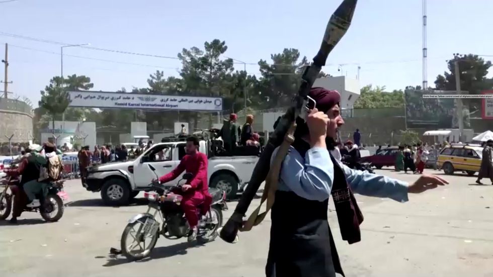 A Taliban fighter runs towards crowd outside Kabul airport, Kabul, Afghanistan August 16, 2021.