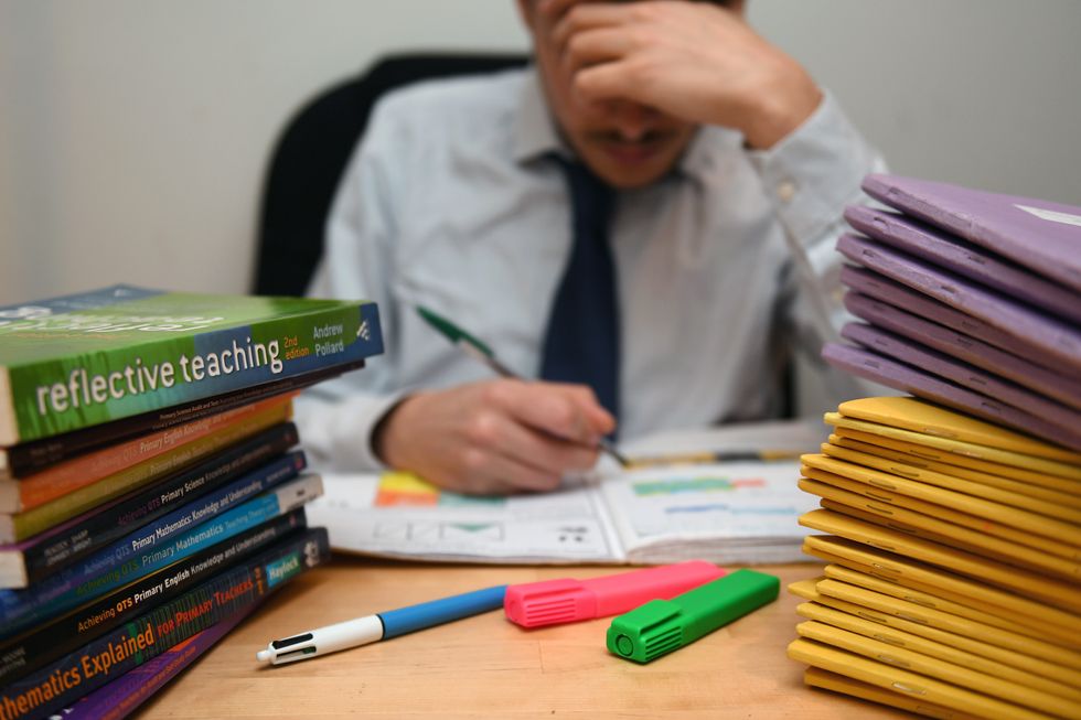 A teacher next to piles of classroom books