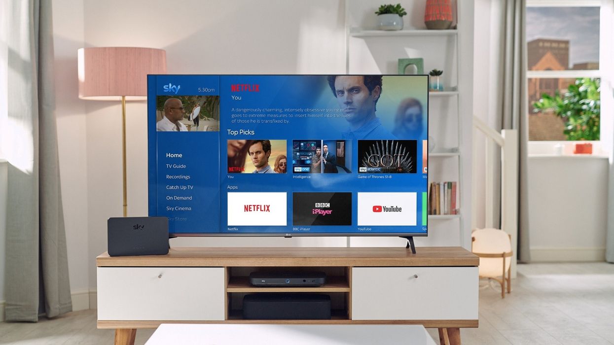 a television on a cabinet shows the Sky TV main menu with Netflix shows included in the recommendations