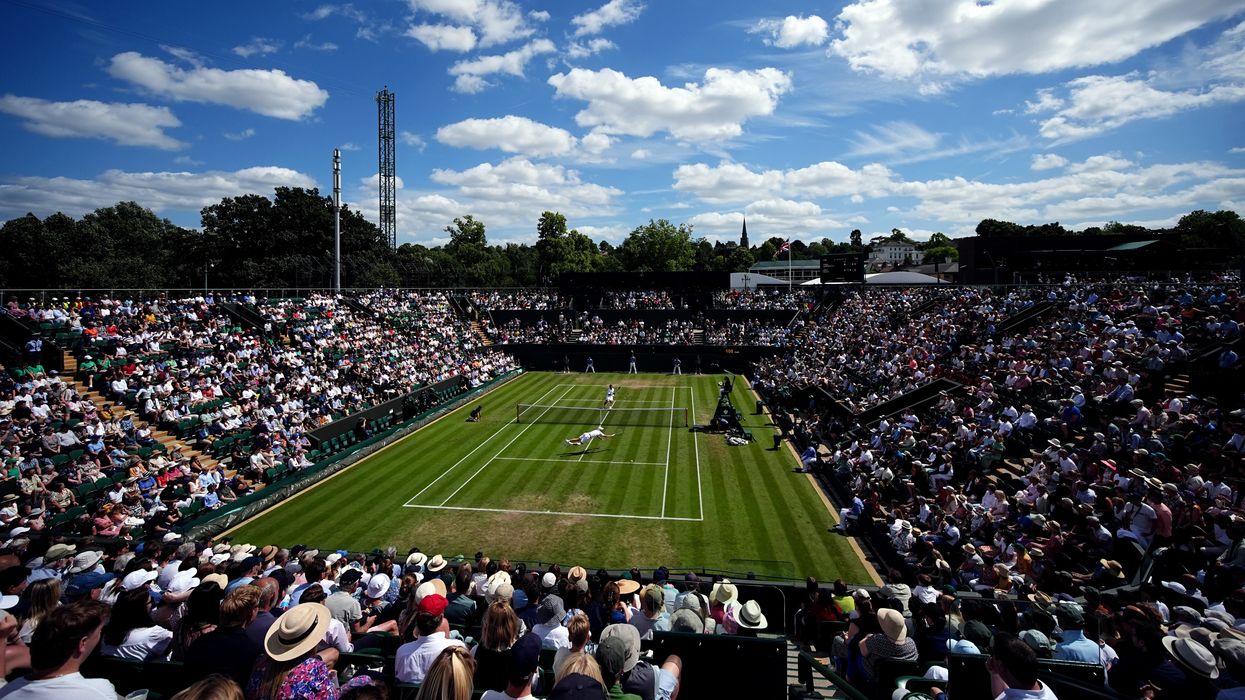 a tennis player wearing white dives to return a ball