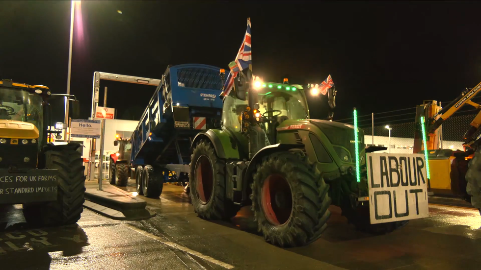 A tractor rolls up to a distribution centre with a 'LABOUR OUT' placard