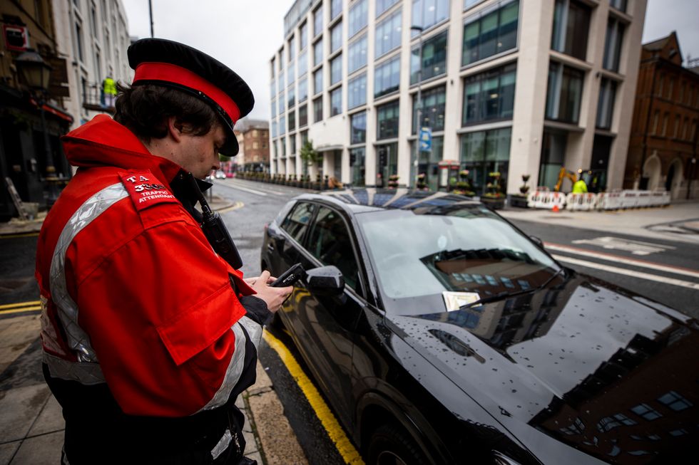 A traffic warden places a warning ticket on a vehicle in Belfast city centre as the lockdown suspension of on-street parking charges in Northern Ireland is set to be lifted. Wardens will issue %22warnings%22 to prepare the public for the return of charges and fines on June 29.