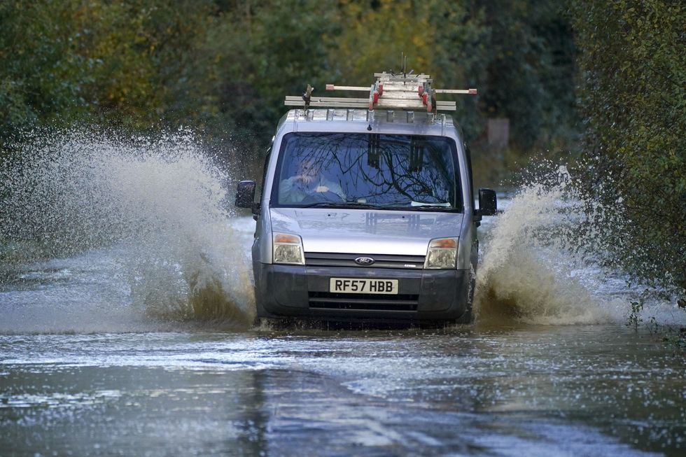 A van drives through flood water on a road in Lingfield, Surrey