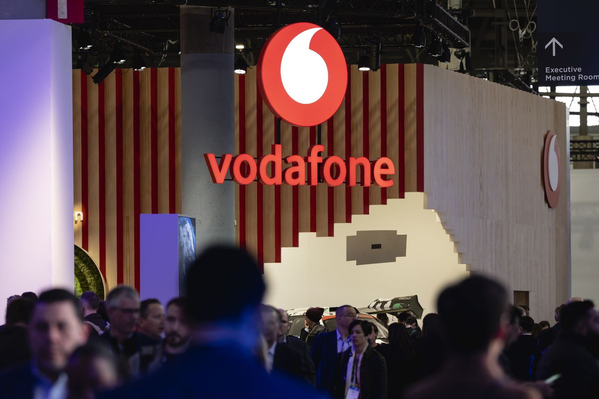 a vodafone sign hangs above a crowd of people 