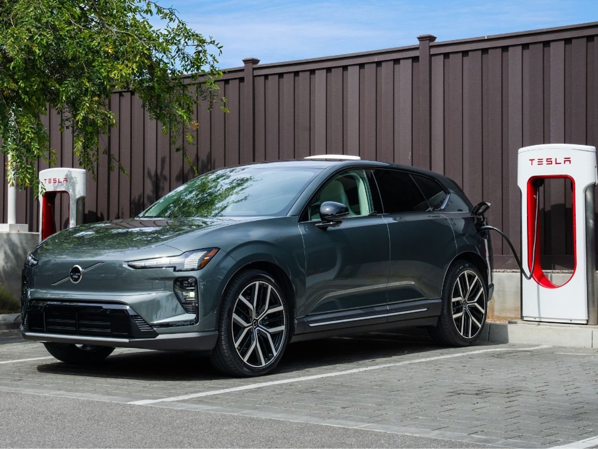 A Volvo electric car charging at a Tesla Supercharger