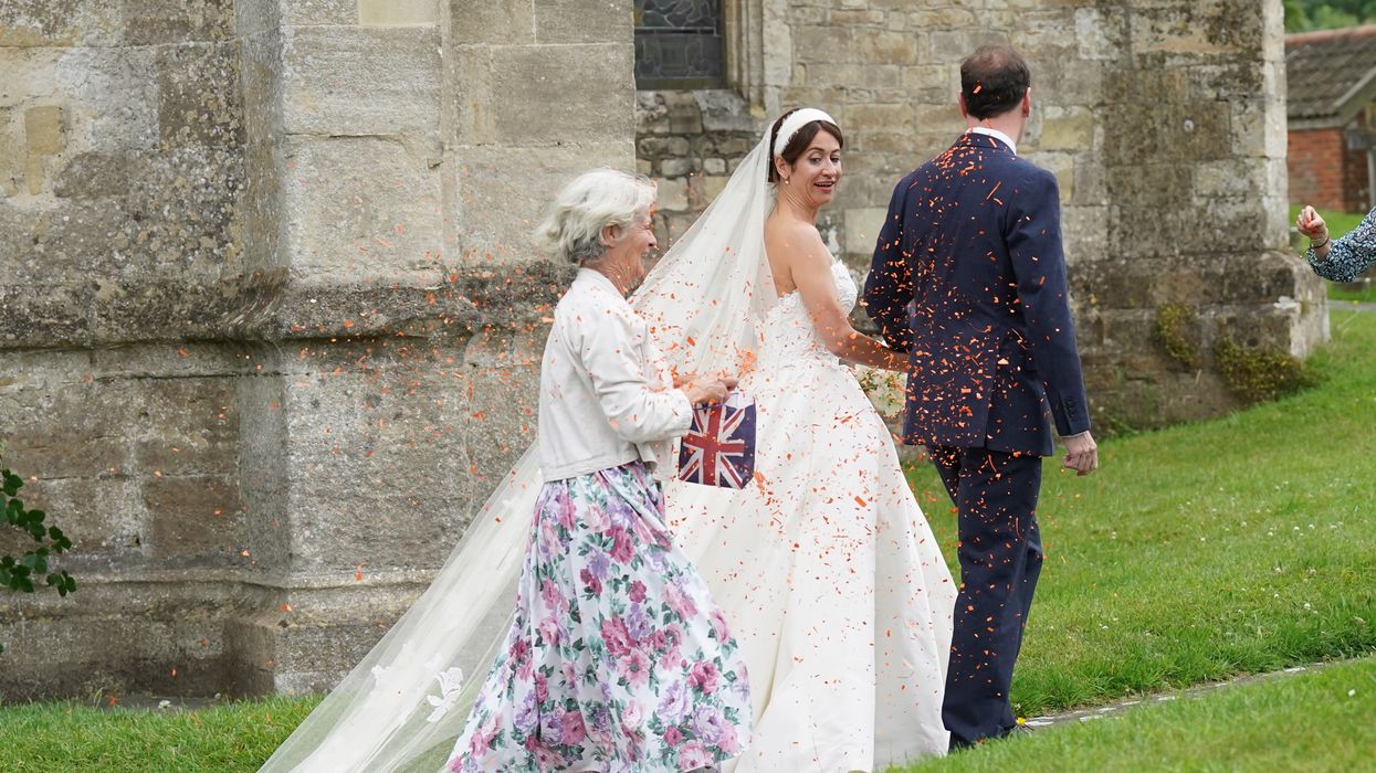 A woman believed to be a Just Stop Oil protester throws orange confetti over former chancellor George Osborne and his wife and former adviser, Thea Rogers