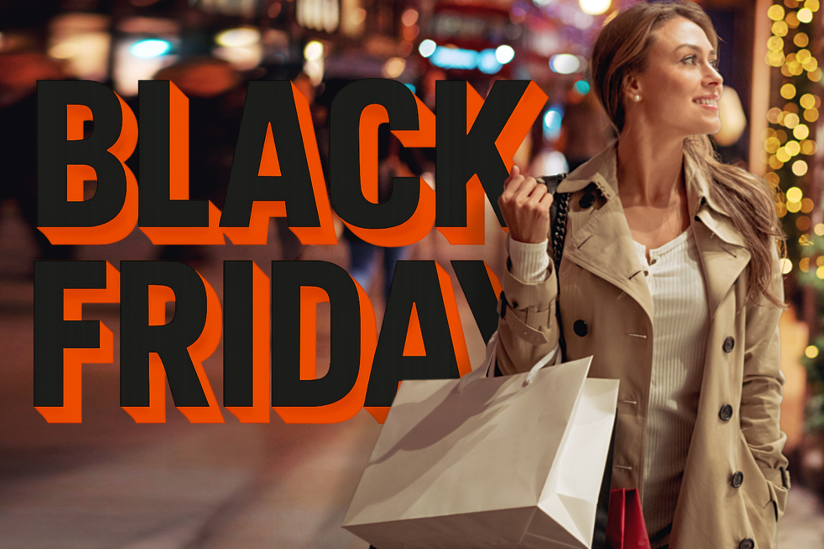 a woman carrying shopping bags down the high street with the black friday sign behind him