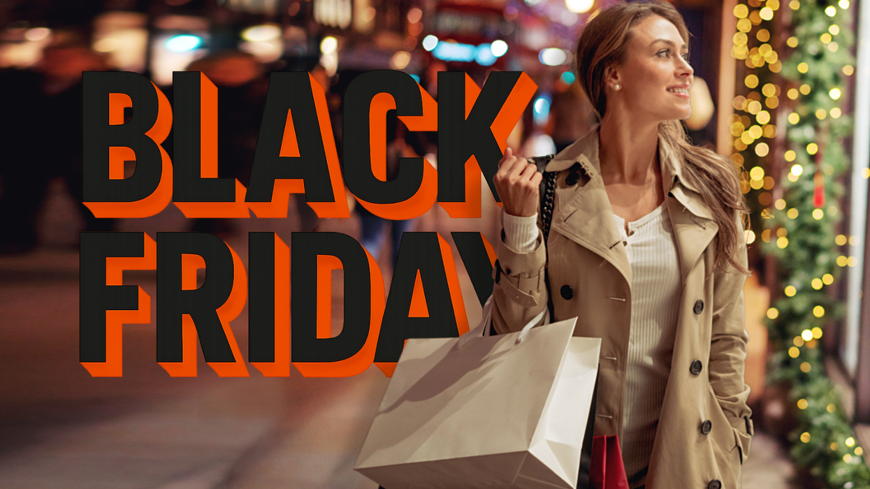 a woman carrying shopping bags down the high street with the black friday sign behind him