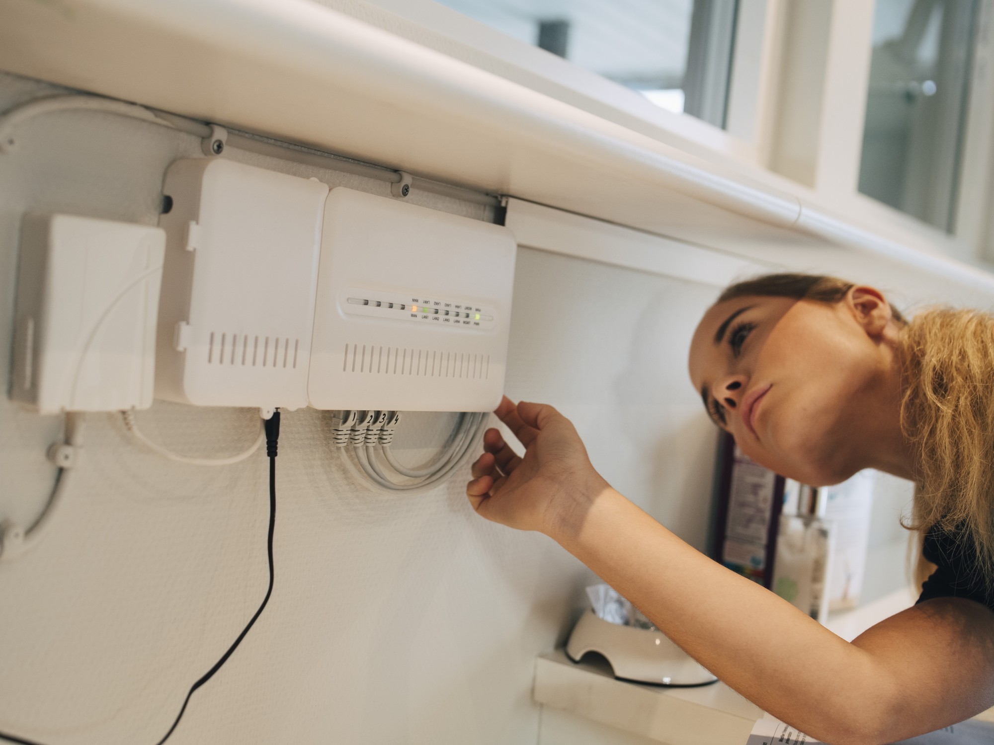 a woman check the ethernet cables connected to her wi-fi router