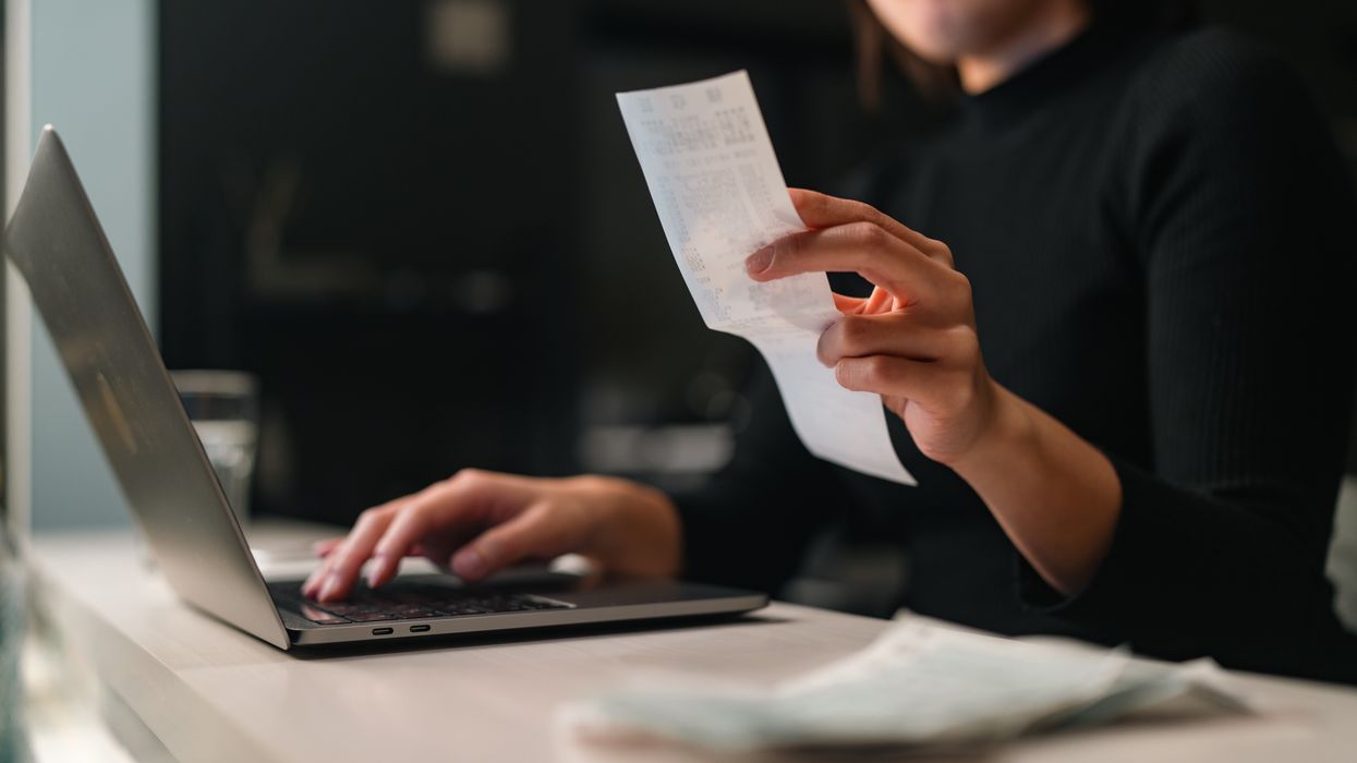 a woman checks receipts for bills while working on her laptop