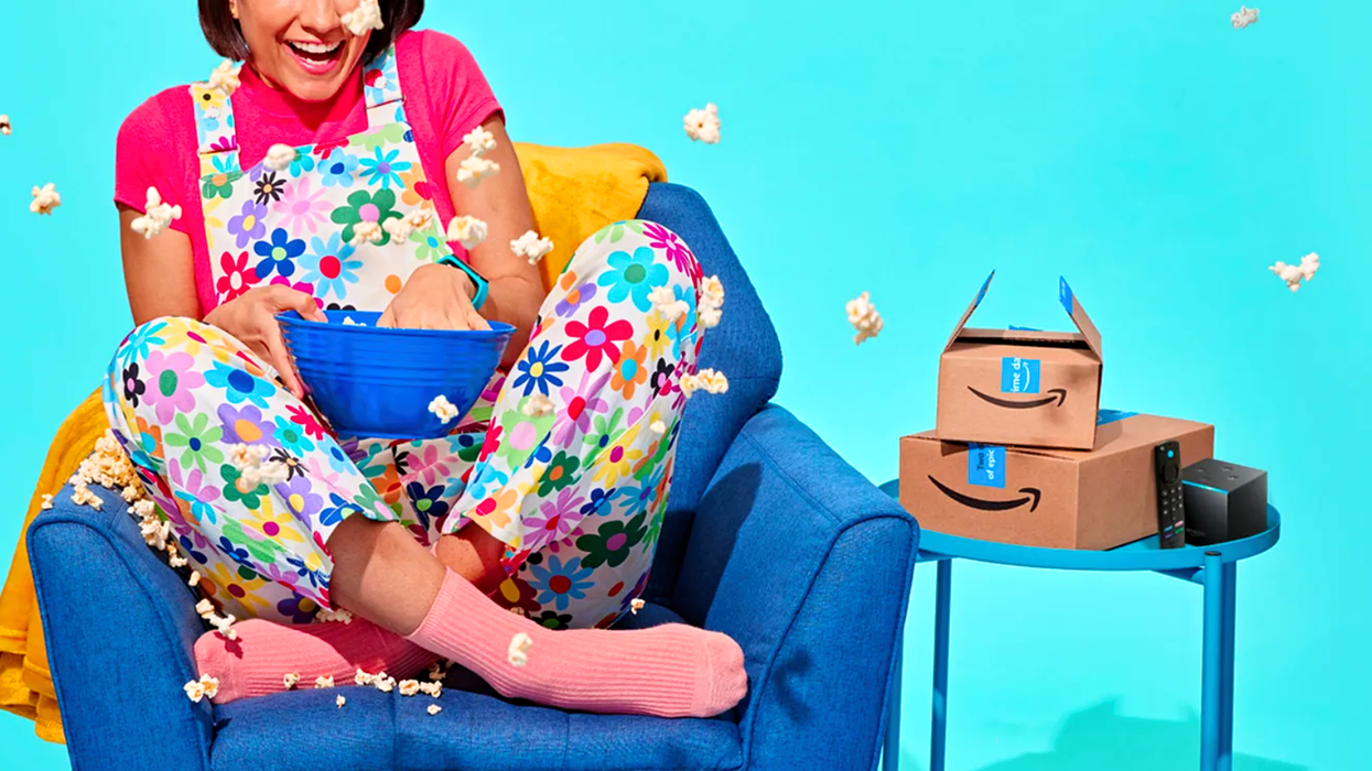 a woman eats popcorn on a sofa with amazon branded boxes next to her and a fire tv stick on a table