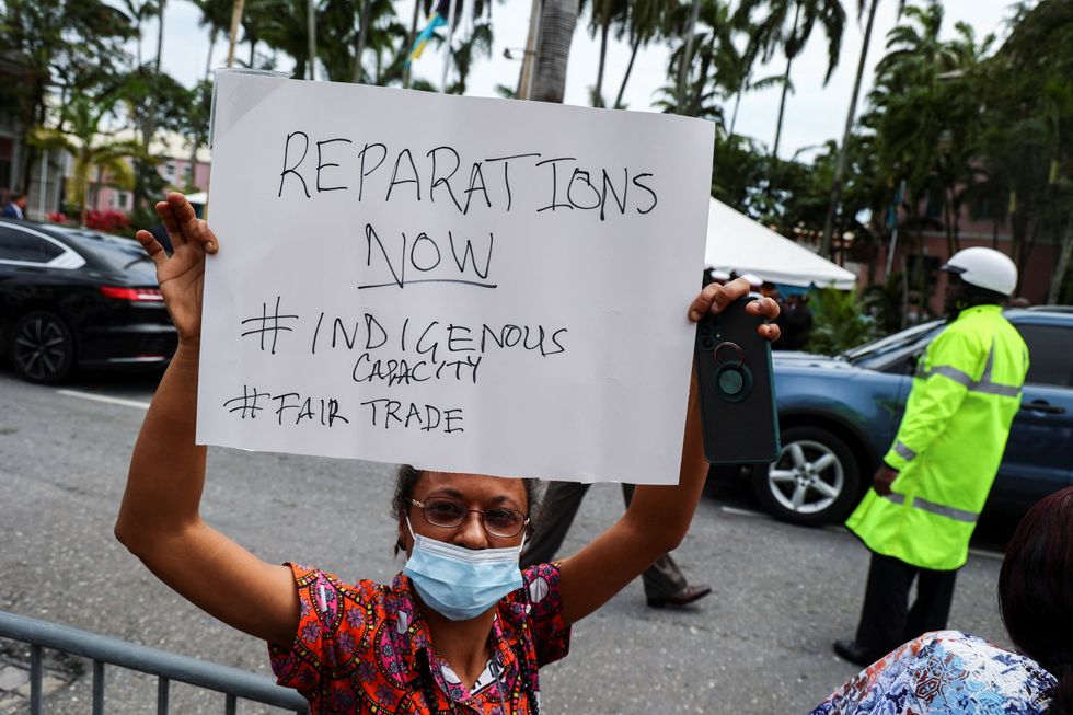 A woman holds a protest sign during a Royal visit of Britain's Prince William and Catherine, Duchess of Cambridge, in Nassau, Bahamas.