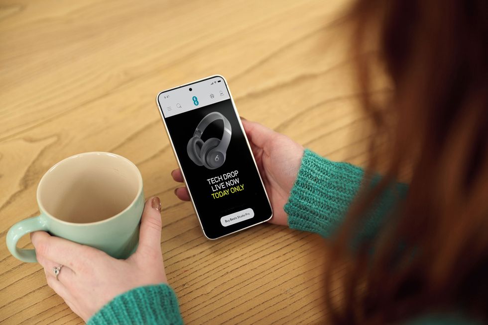 a woman holds her phone with the ee tech drop pictured on-screen