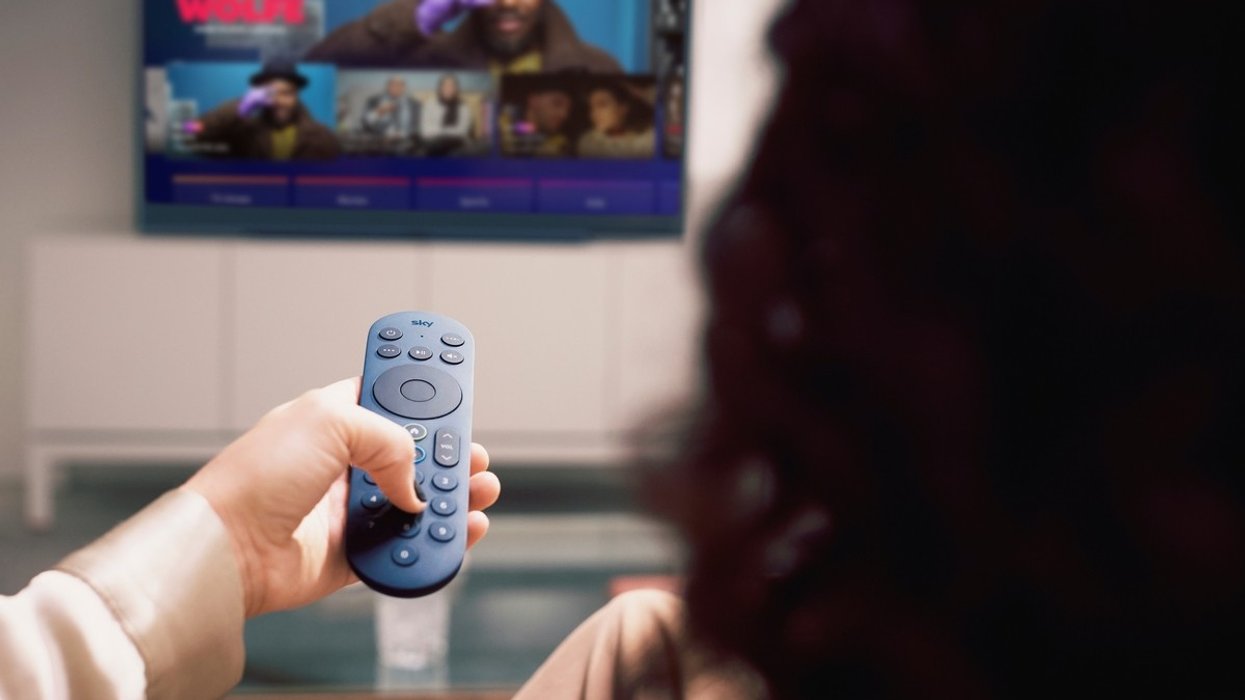 a woman holds out a blue sky glass remote control to change channels