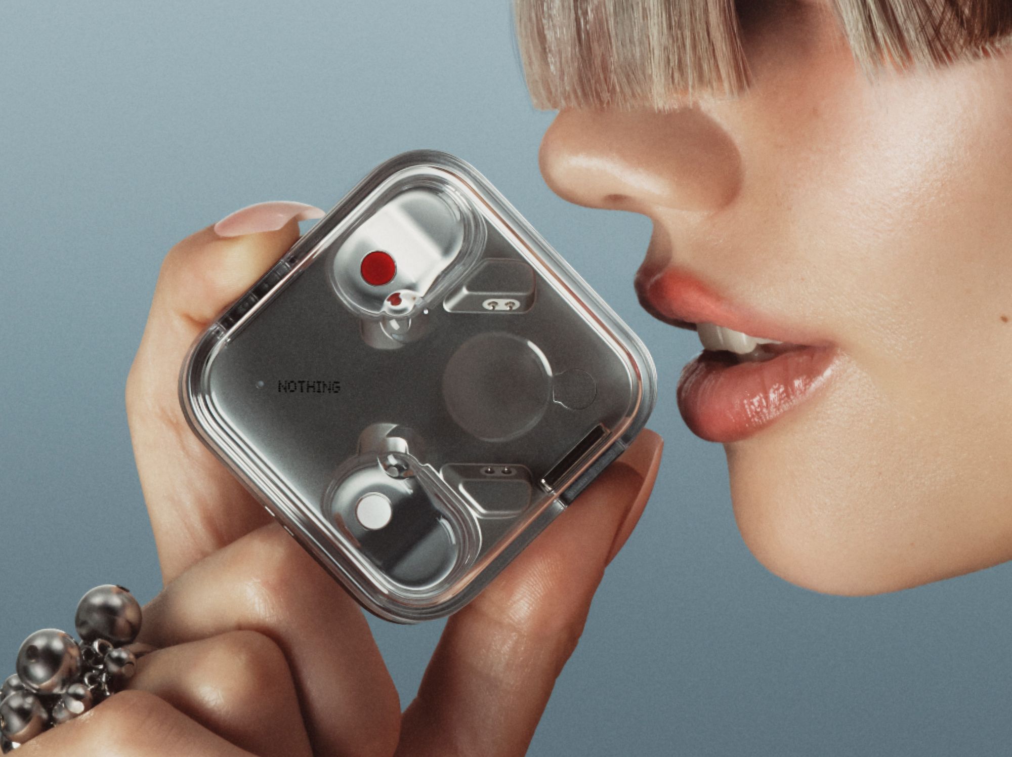 a woman holds the Nothing Ear 3 case close to her mouth