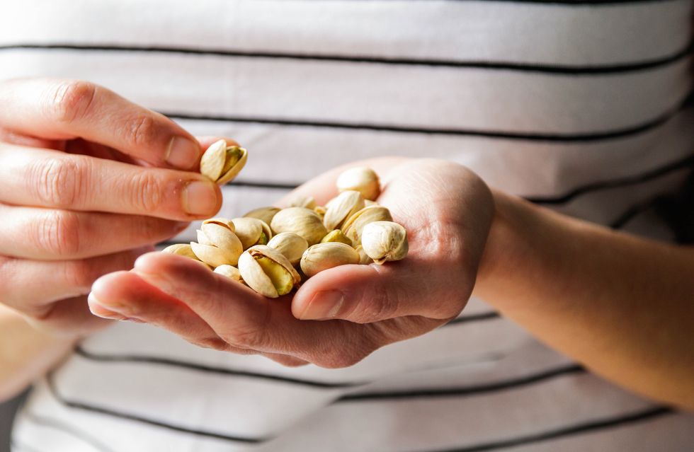 A woman in a stripy shirt holding a handful of pistachios