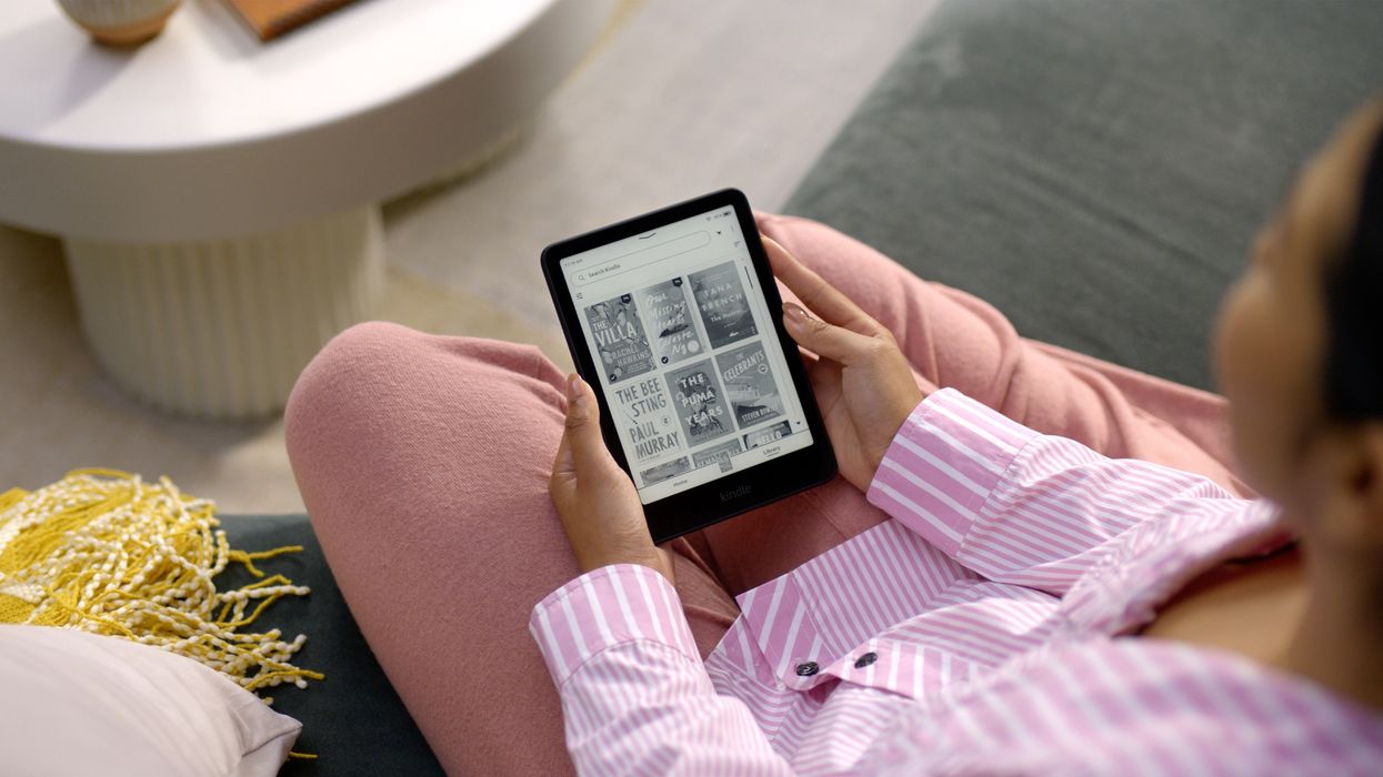 a woman in pink pyjamas can be seen browsing through book covers on her black and white kindle ereader