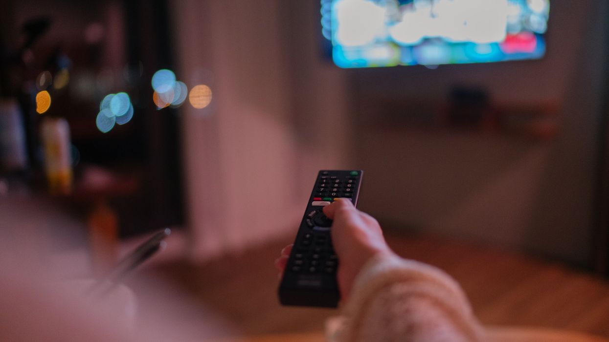 a woman is pictured holding a remote control pointed at an out of focus television