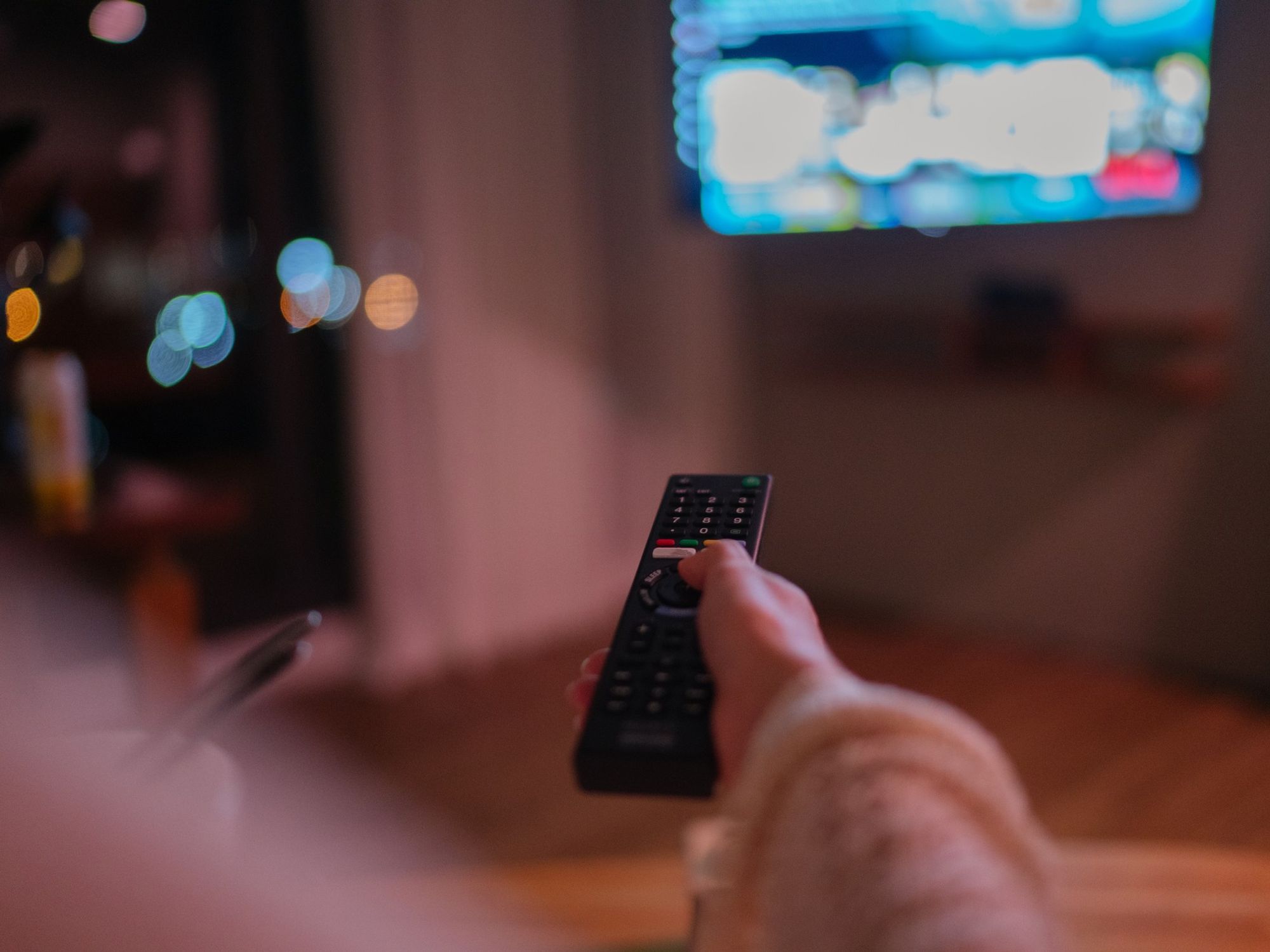 a woman is pictured holding a remote control pointed at an out of focus television