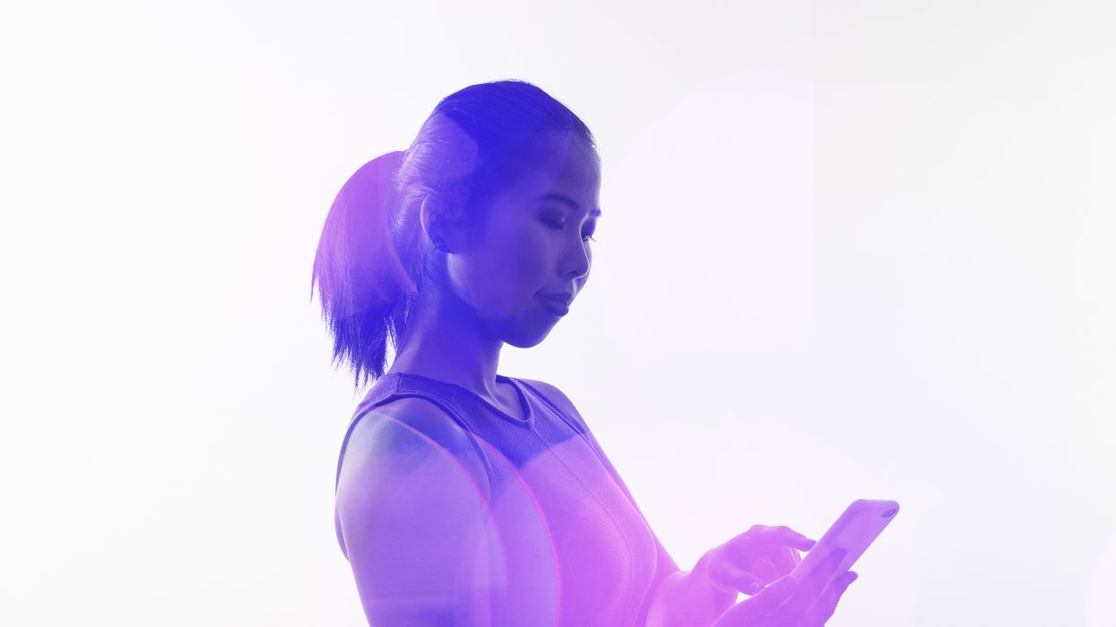 a woman is pictured typing a text message onto her smartphone with a filter of different colours surrounding her