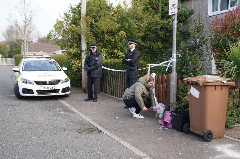 A woman lays flowers at a house in St Helens after a 17-month-old girl died after being attacked by a dog. Merseyside Police said officers received a report at 3.50pm on Monday that a child had been attacked by a dog at an address on Bidston Avenue, Blackbrook. Picture date: Tuesday March 22, 2022.