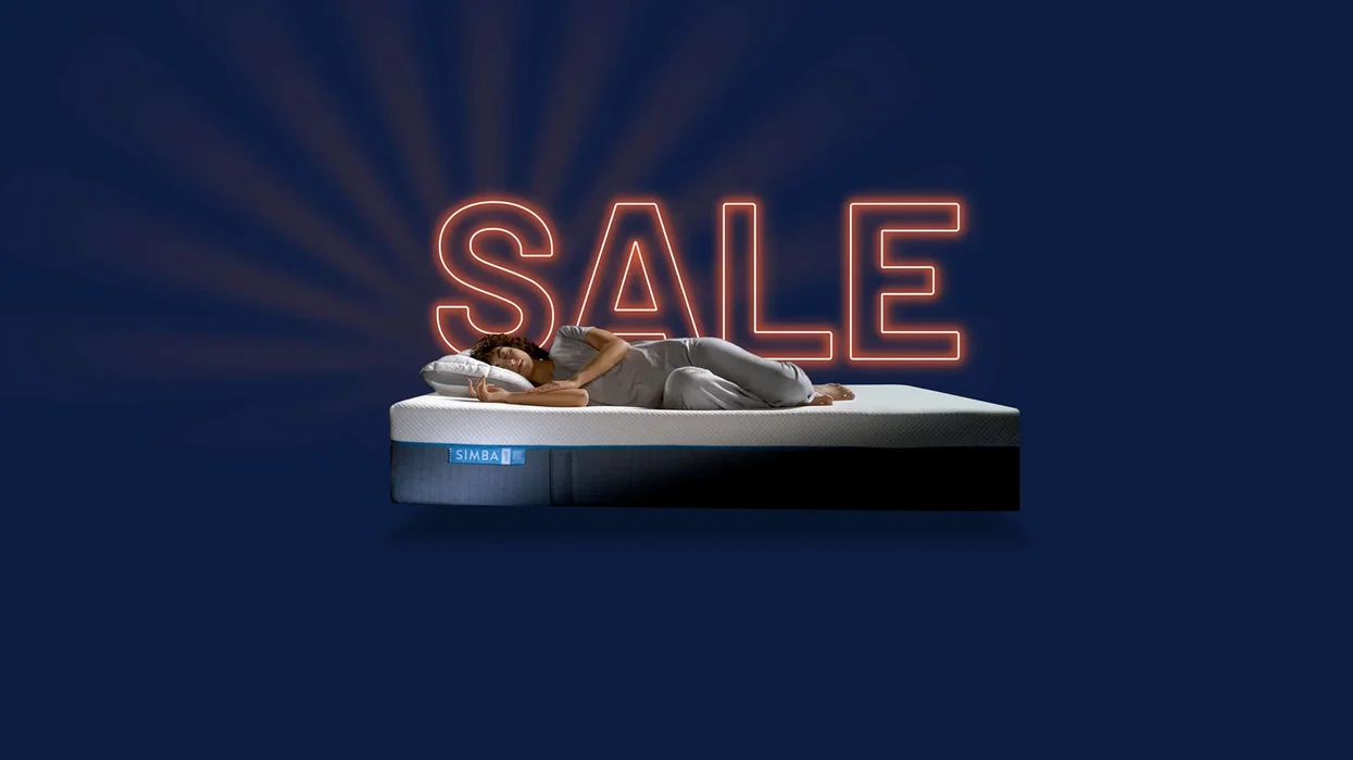 a woman lies on her side on a simba mattress on a blue background