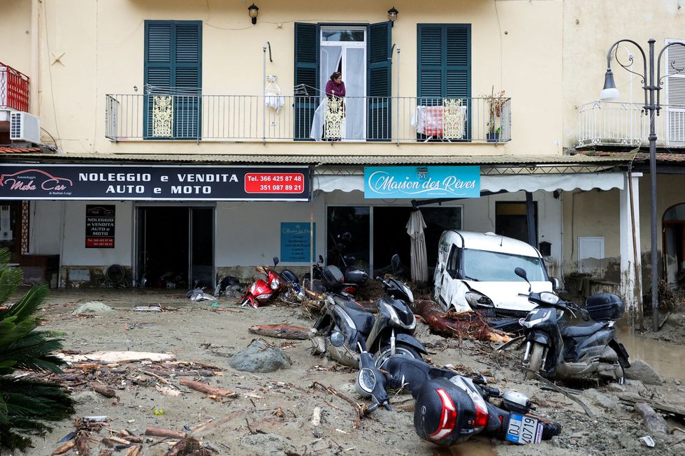 A woman looks from a balcony at a street covered in debris and damaged vehicles following a landslide on the Italian holiday island of Ischia, Italy November 26, 2022. REUTERS/Ciro de Luca     TPX IMAGES OF THE DAY