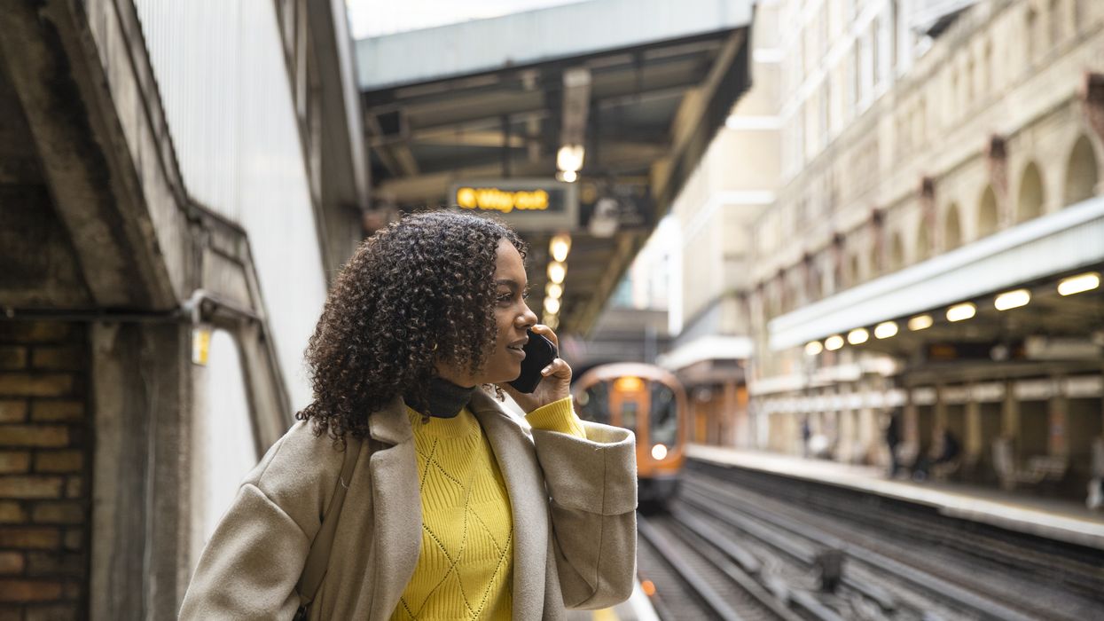 a woman makes a phone call on the platform of a London Underground train