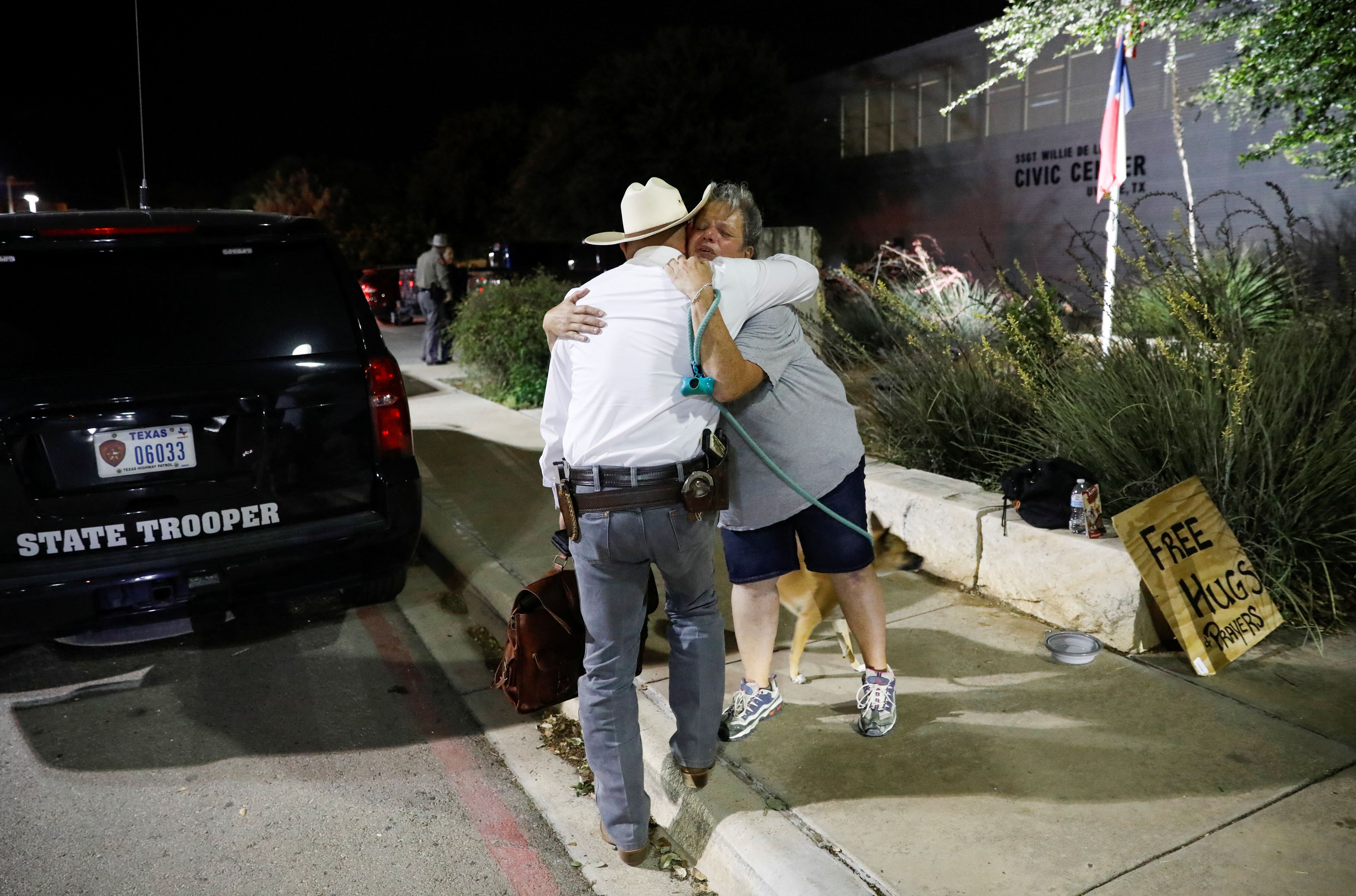 A woman offering hugs and prayers embraces a Texas Ranger outside the Ssgt Willie de Leon Civic Center, where students had been transported from Robb Elementary School after a shooting, in Uvalde, Texas, U.S.