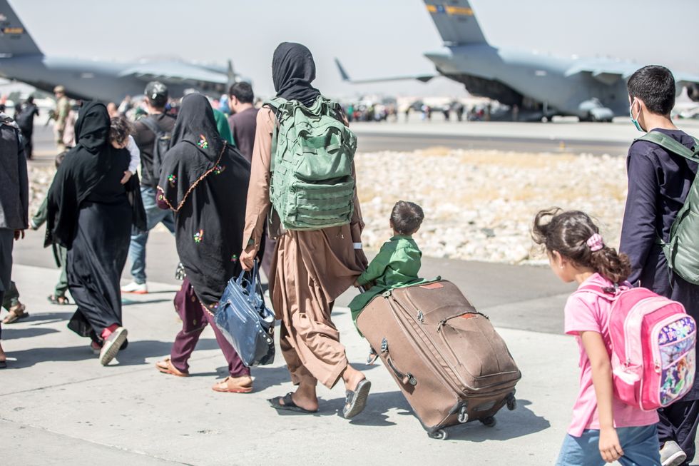 A woman pulls a suitcase with a child sitting on top during an evacuation at Hamid Karzai International Airport, Kabul, Afghanistan.