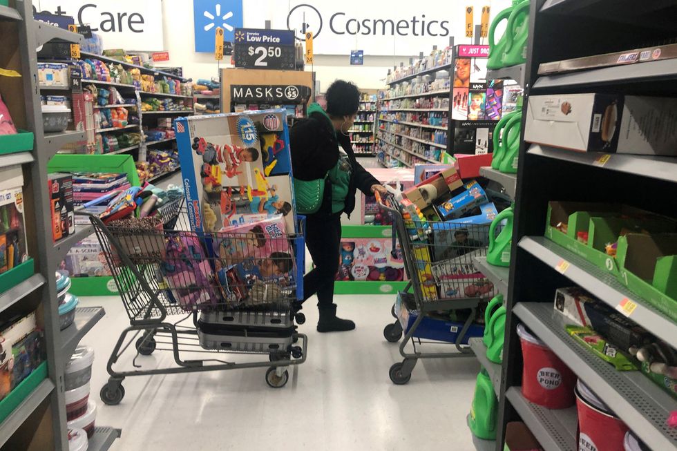 A woman pushes shopping carts during a sales event on Thanksgiving day at Walmart in Westbury