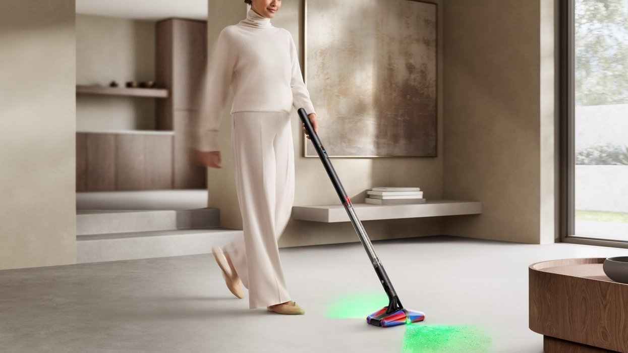 a woman pushes the dyson pencilvac on the floor with the laser guides showing at the front and back