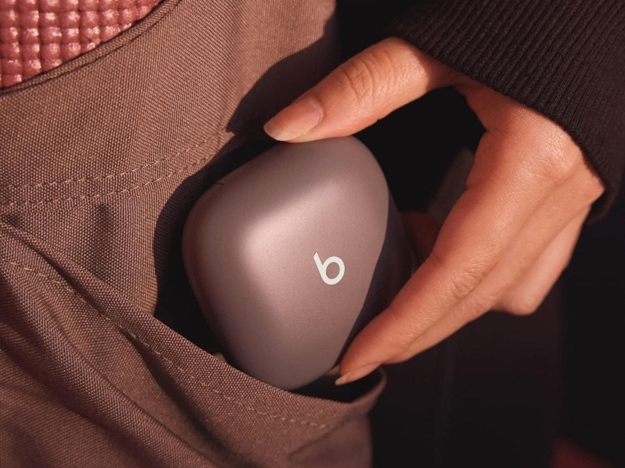 a woman puts the beats fit pro case in her pocket