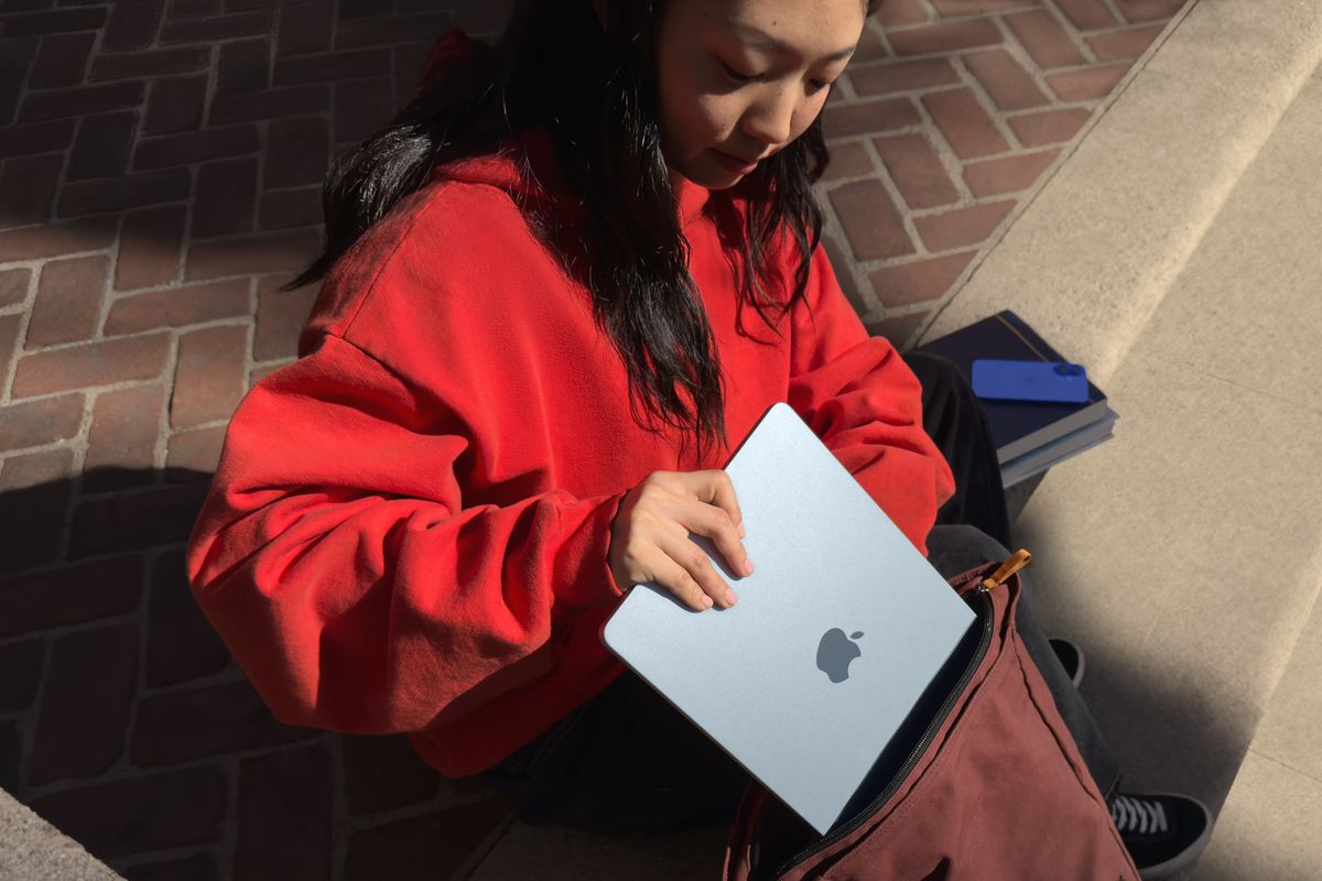 a woman puts the new sky blue macbook air in her rucksack